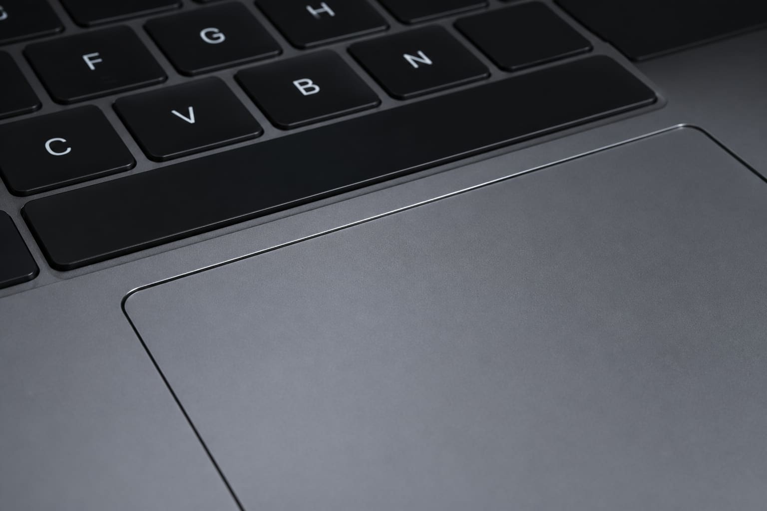 Close-up of MacBook Pro keyboard and trackpad in low light